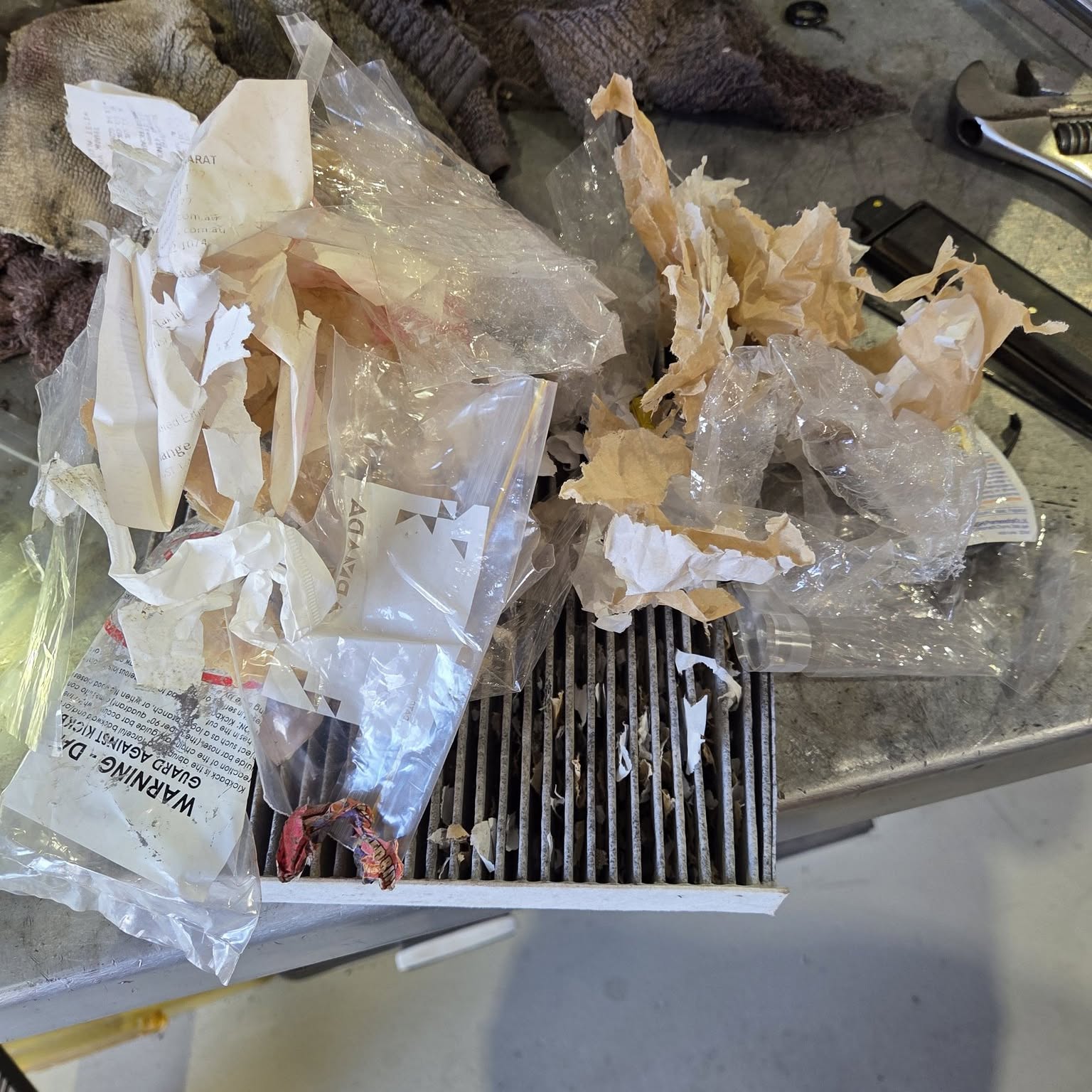 A cabin air filter covered in shredded paper and plastic from a rodent nest