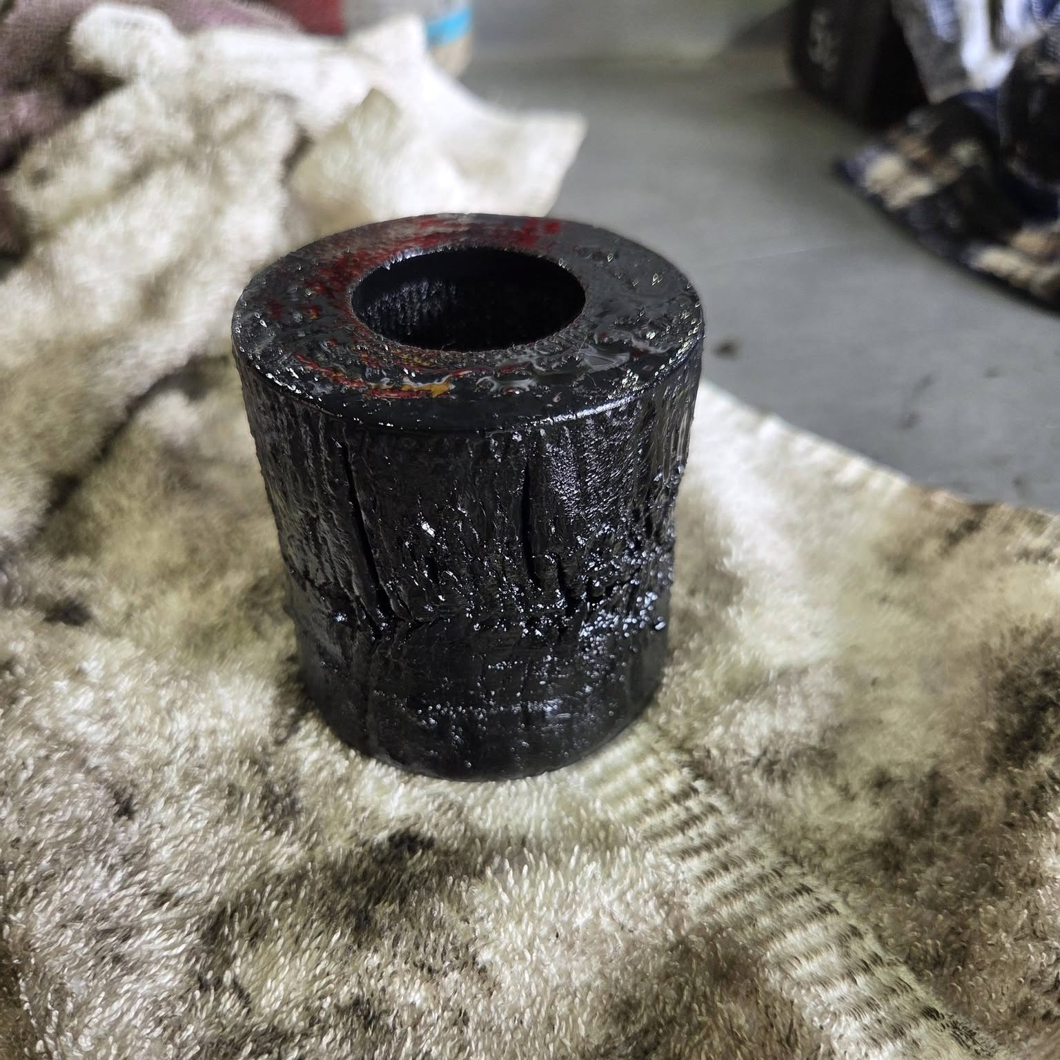 A perished and cracked black rubber suspension bush resting on a workshop rag